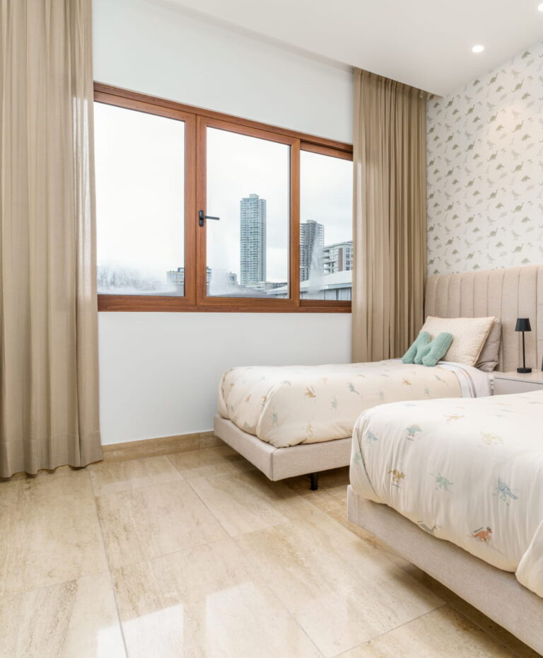 Habitación con dos camas individuales, cabecera tapizada y ventana amplia con vista urbana en The Woods Santa María.